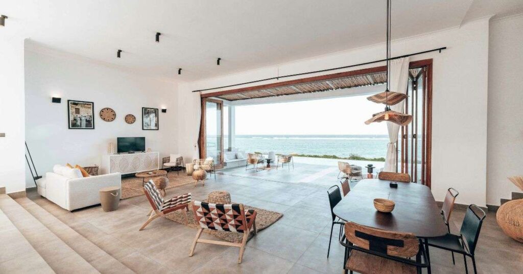 Modern open-plan living and dining room with sea view, minimalist furniture, and natural interior design style.
