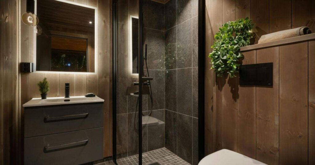 Modern dark bathroom design with wooden walls, LED mirror lighting, glass shower, and stylish space-saving interior decor.