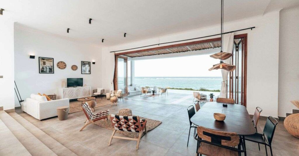 Bright modern open-plan living and dining room with ocean view, stylish furniture, and natural lighting.