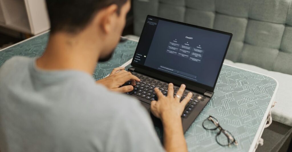 Person typing on laptop with ChatGPT open, working online in a modern digital workspace setting.